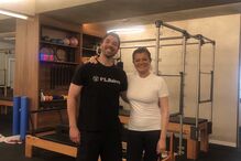 Duas pessoas posam num estúdio com equipamentos de pilates