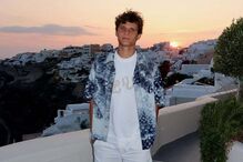 Um jovem posa em Santorini ao pôr do sol