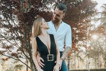 Casal sorri num jardim, com o sol a brilhar