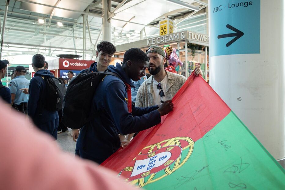 Jogador autografa uma bandeira de Portugal de um adepto à chegada ao aeroporto
