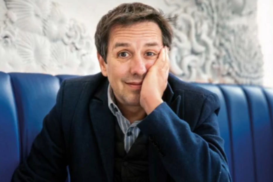 Retrato de homem com blazer azul num sofá acolchoado azul