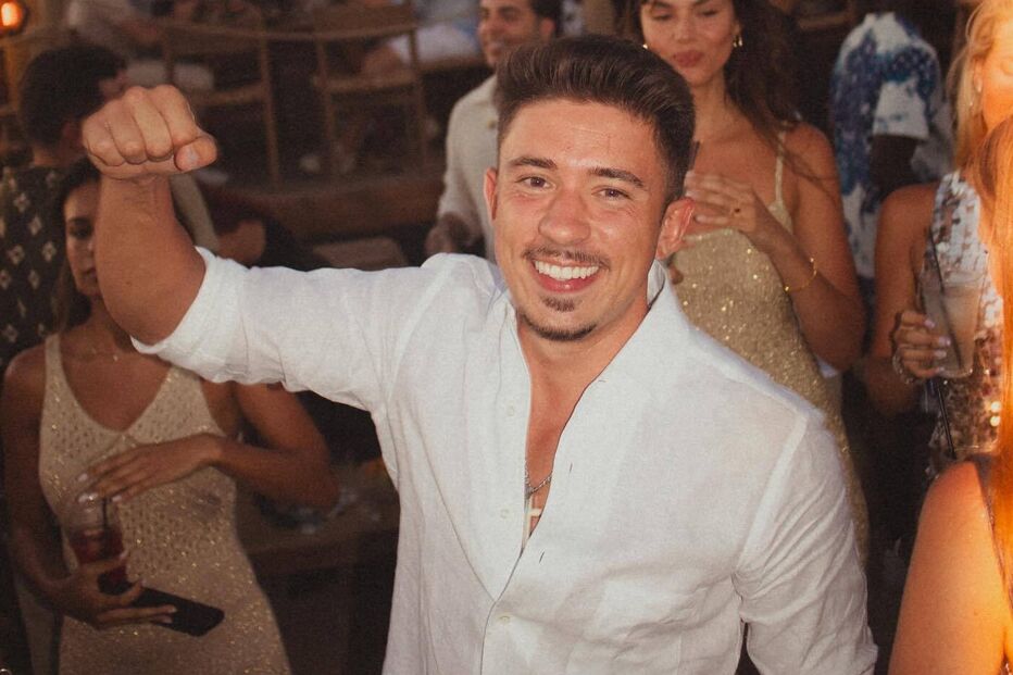 Um homem sorri numa festa com outras pessoas