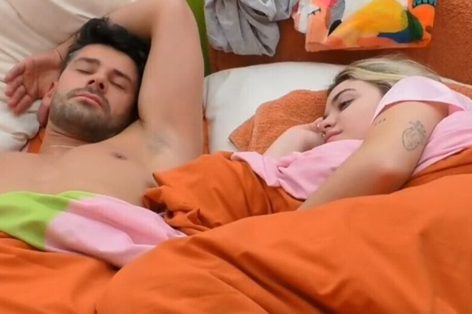 Homem e mulher deitados numa cama com lençóis laranja