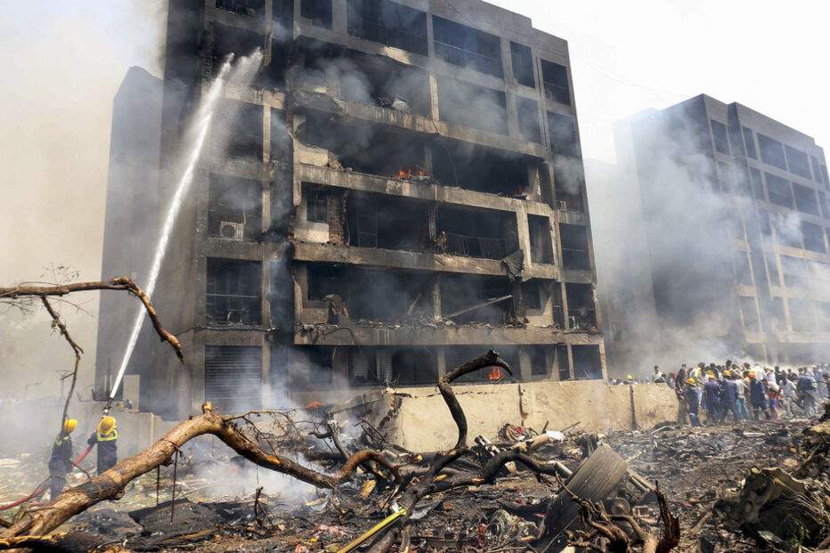 Bombeiros combatem incêndio em edifício danificado, com destroços no local