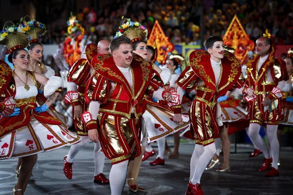 Pessoas festejam com trajes de cartas de jogar num evento carnavalesco