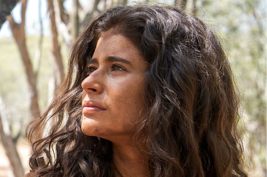 Atriz caracteriza personagem em cenário de vegetação seca