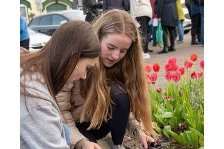 Jovens acendem velas num tributo com flores vermelhas