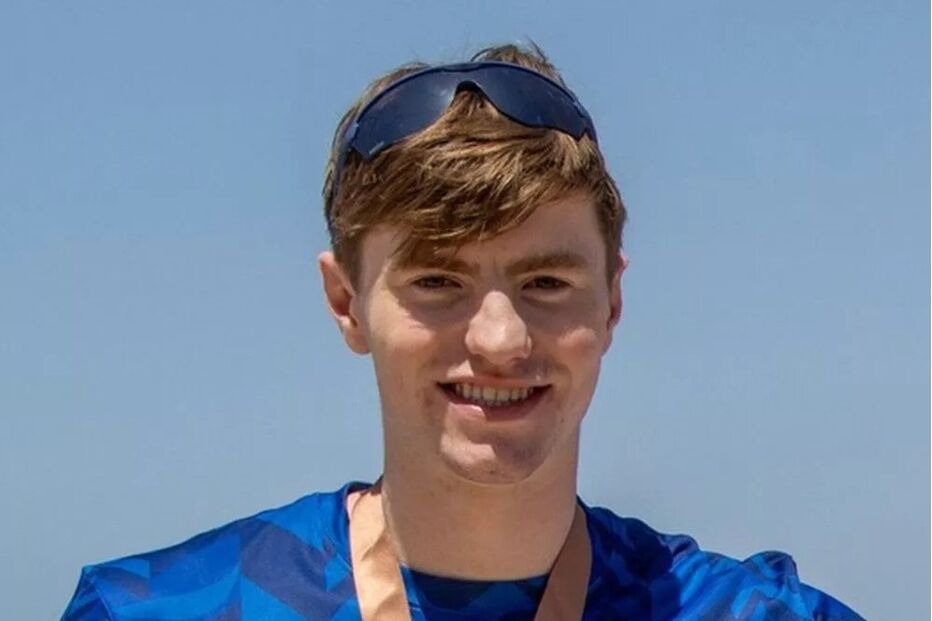 Homem sorridente com óculos de sol e medalha