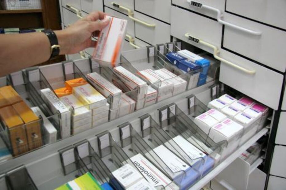 Mão retira embalagem de medicamento em farmácia