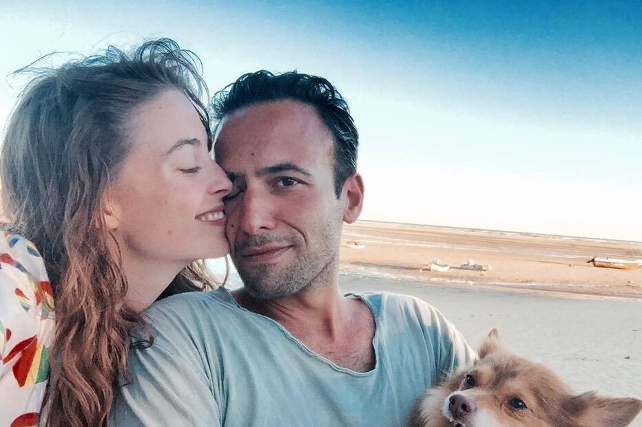 Um casal e um cão numa praia aproveitam o dia