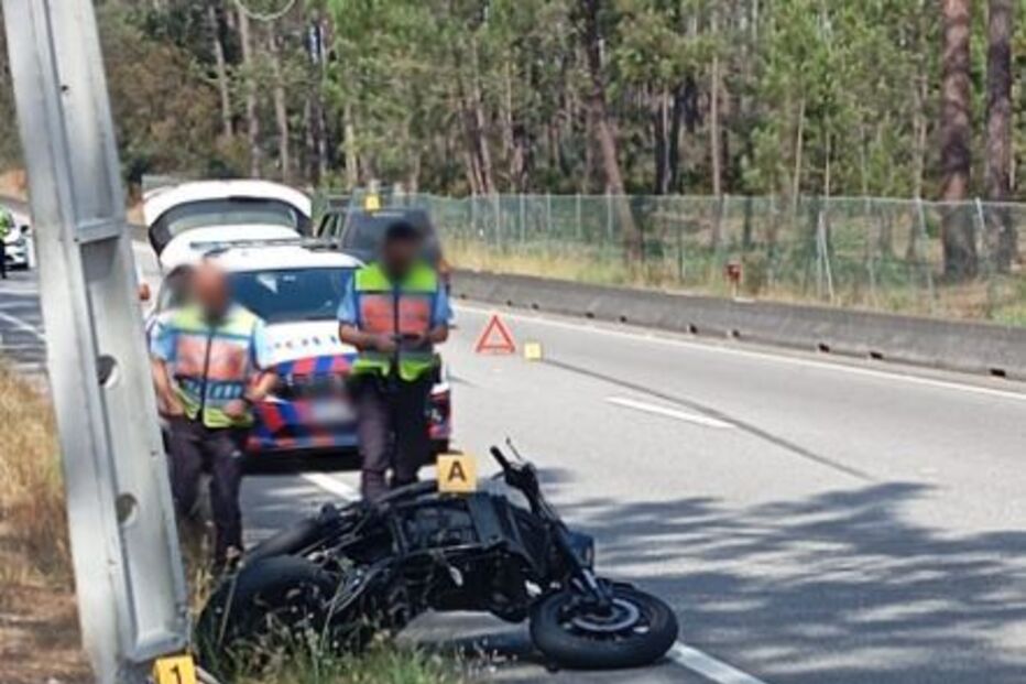 Motociclo envolvido em acidente na estrada, com agentes da polícia no local