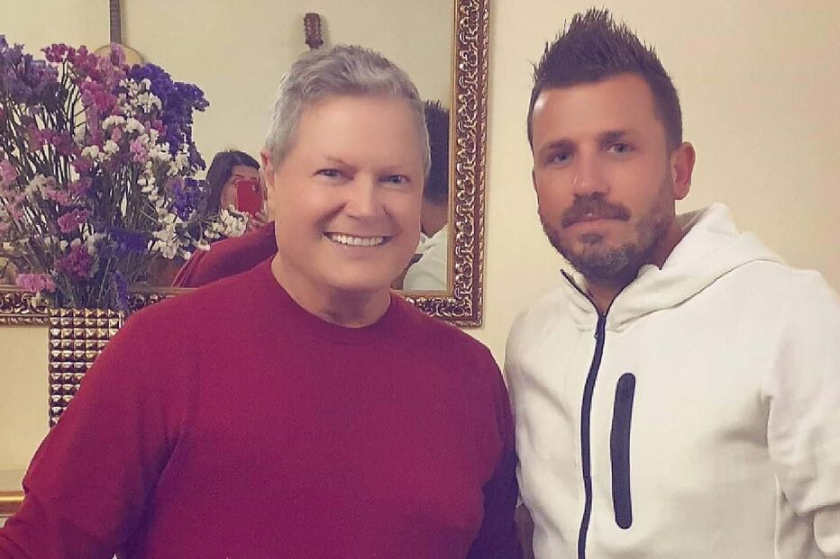 Dois homens posam juntos para uma fotografia