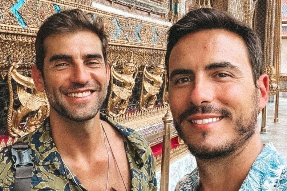 Dois homens sorriem em frente ao templo Wat Arun Ratchawararam Ratchawaramahawihan, em Bangkok