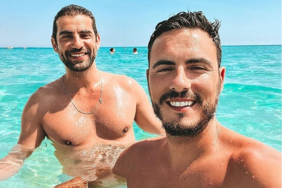 Dois homens sorriem na água azul e cristalina