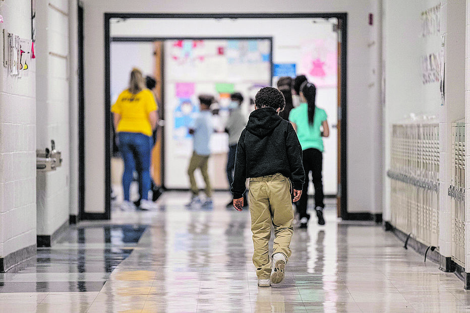 Crianças caminham num corredor de escola com cacifos