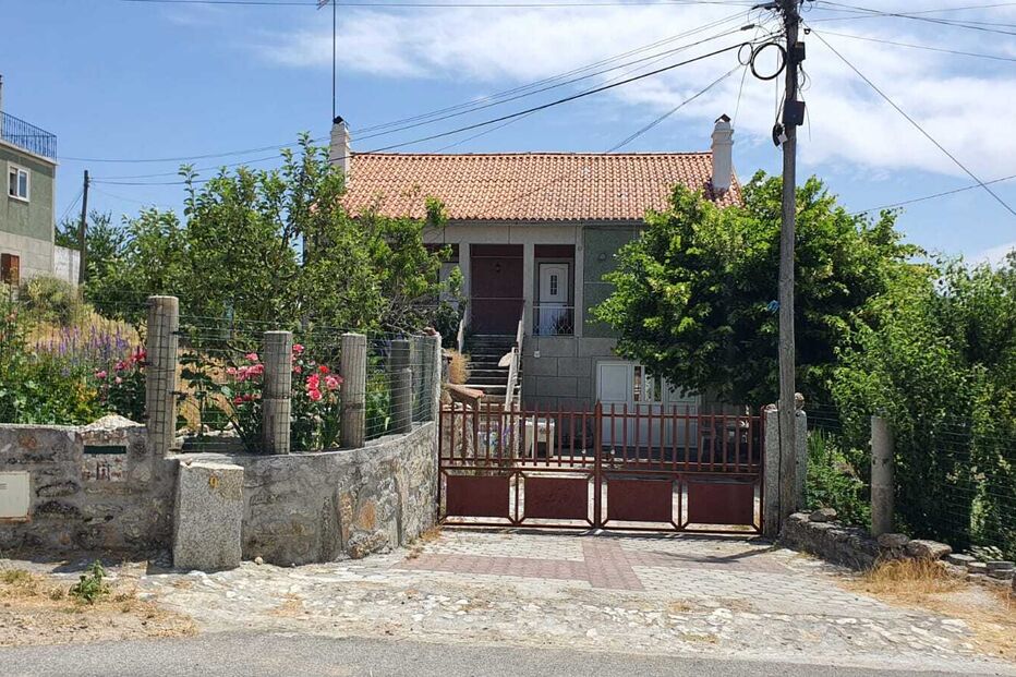 Casa rústica com portão de ferro e jardim florido na fachada