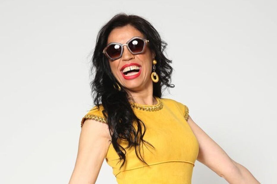 Mulher sorri com óculos de sol e vestido amarelo