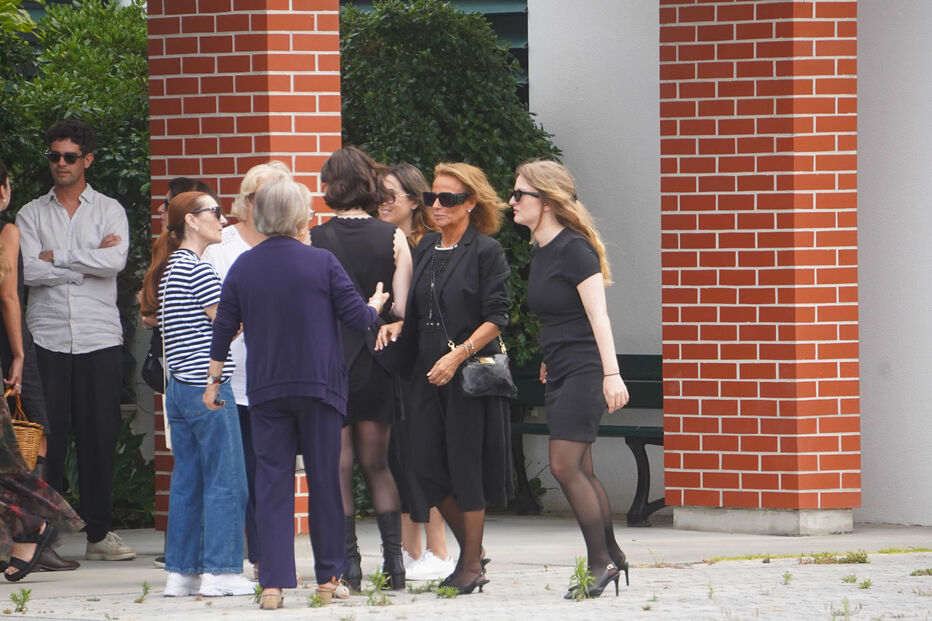 Um grupo de pessoas reunido ao ar livre junto a uma estrutura de tijolo