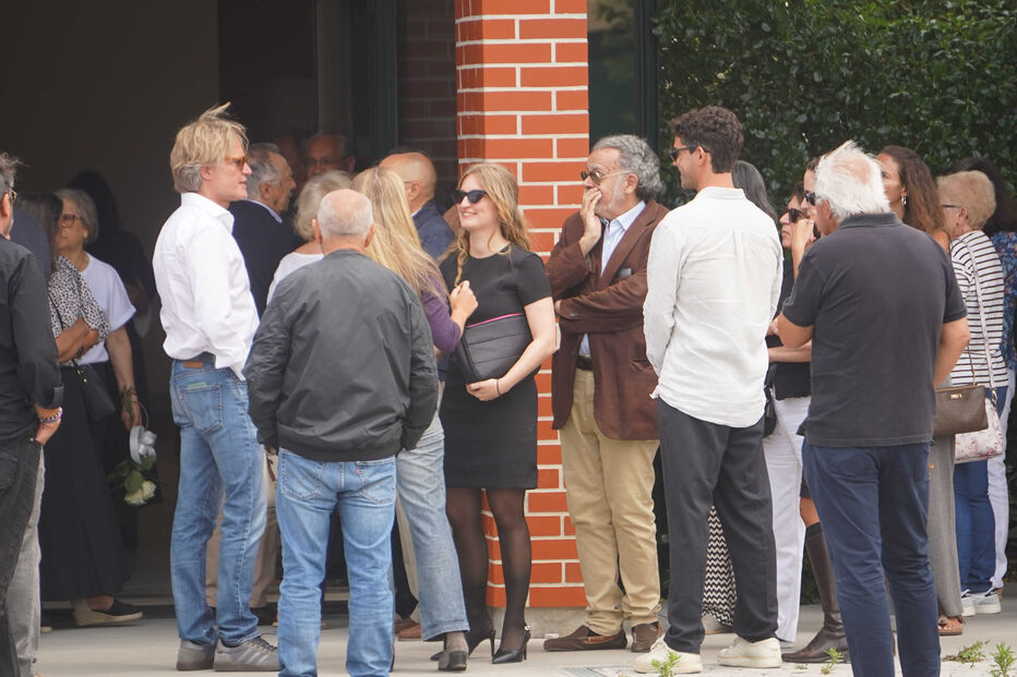 Pessoas reunidas junto a um edifício de tijolo vermelho, com roupas informais