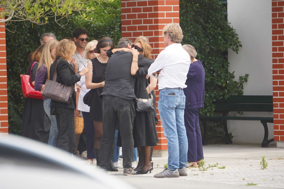 Pessoas reúnem-se e oferecem apoio em cerimónia.
