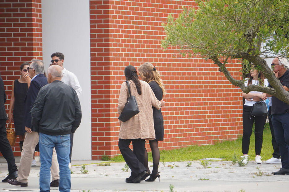 Um grupo de pessoas reunido perto de um edifício de tijolos