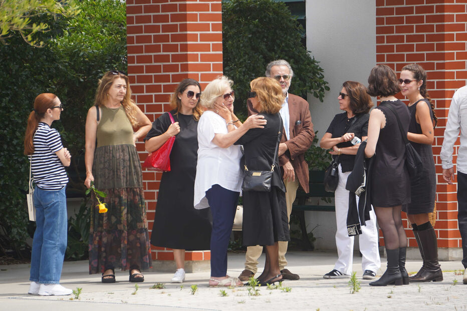 Um grupo de pessoas reunidas, duas mulheres abraçam-se