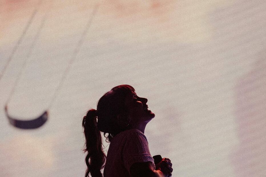 Silhueta de Lorde durante apresentação, com microfone e rabo de cavalo