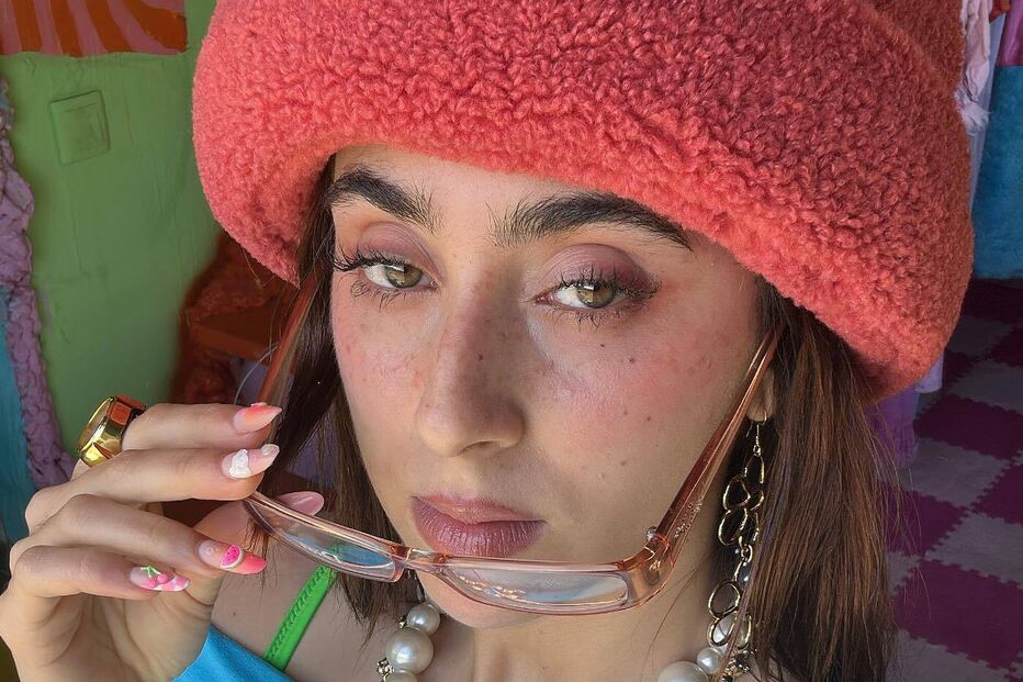 Mulher com chapéu rosa, óculos e colar de pérolas