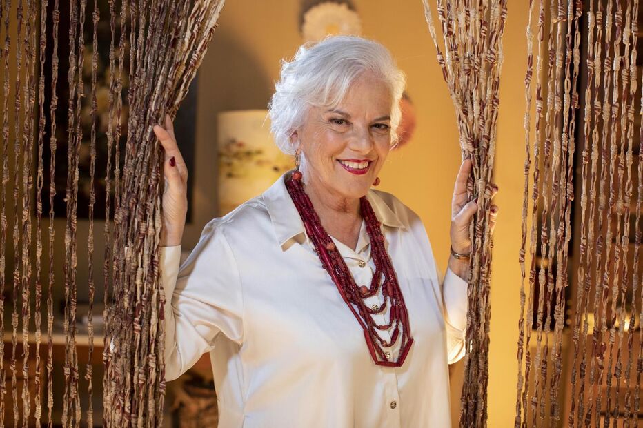 Atriz sorri com colar vermelho e camisa branca