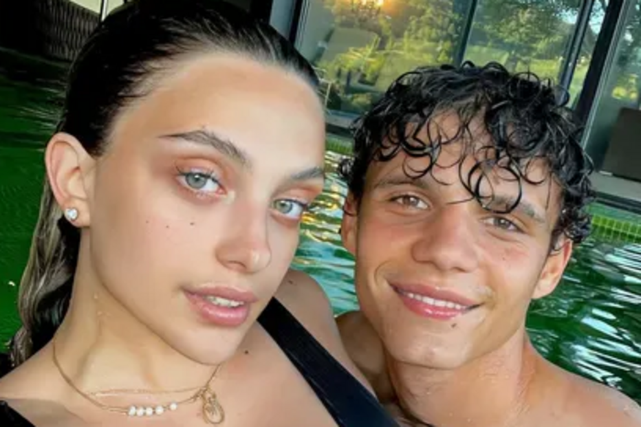 Casal posa sorridente numa piscina com vista para a paisagem