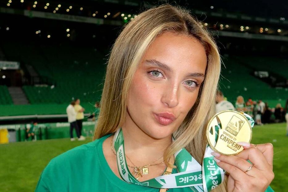 Mulher sorri com medalha do Sporting CP no estádio