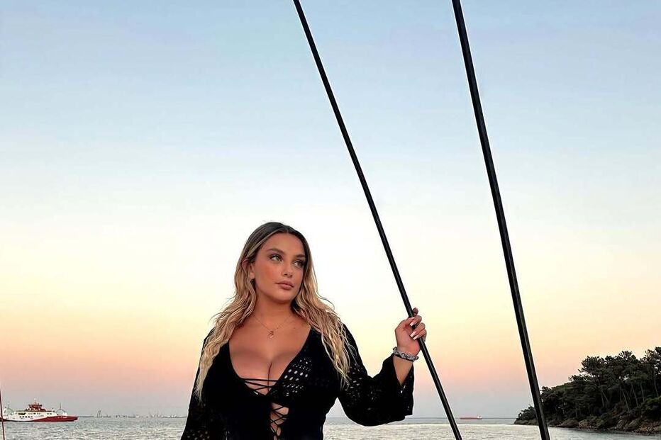 Mulher posa em barco com fato de banho preto e blusa rendada