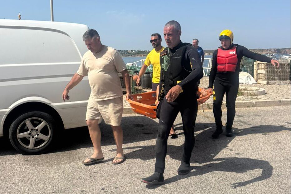 Equipa de resgate transporta vítima numa maca perto de uma carrinha
