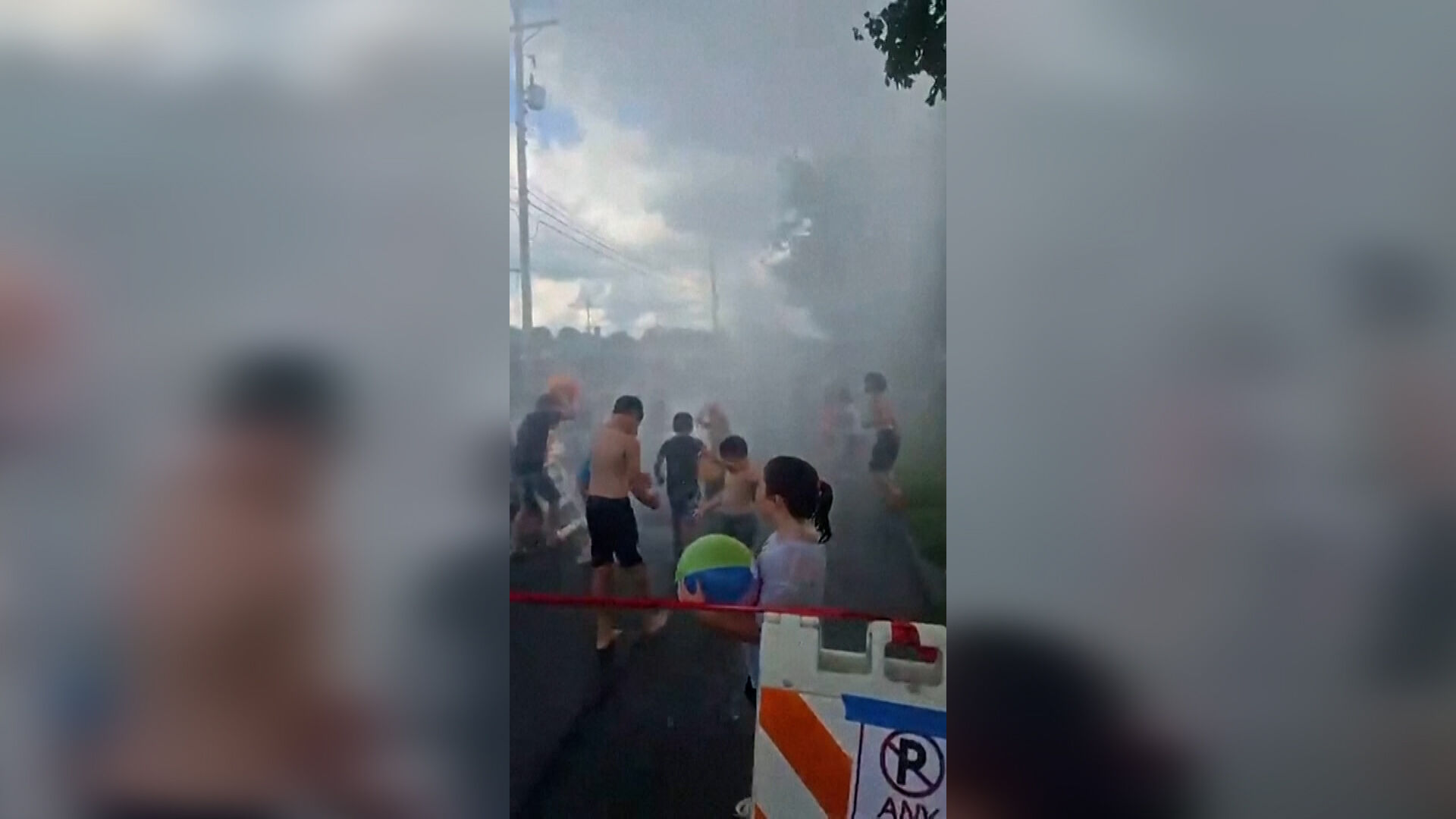 Crianças desfrutam de um jato de água de uma mangueira de incêndio durante um festival de verão