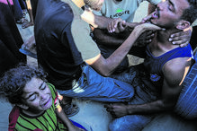 Gaza: Homem ferido recebe auxílio enquanto criança chora, após incidente em centro de distribuição