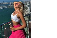 Mulher aproveita vista em Dubai com saia rosa e top branco