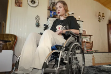 Uma mulher numa cadeira de rodas está dentro de casa