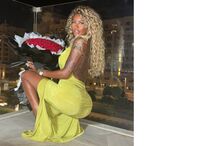 Mulher com vestido verde segura um ramo de rosas vermelhas