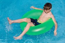 Menino aproveita piscina com boia nas férias de verão