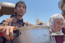 Mahmoud al-Najjar, 24 anos, deslocado palestiniano junto a uma cozinha comunitária onde tenta receber comida, na cidade de Gaza