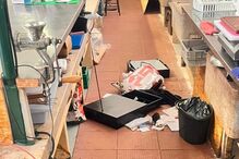 Espaço comercial apresenta desordem, com objetos espalhados no chão e bancadas