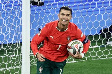 Cristiano Ronaldo sorri com a bola na mão junto à baliza