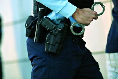 Agente da polícia com arma e algemas perto de suspeito