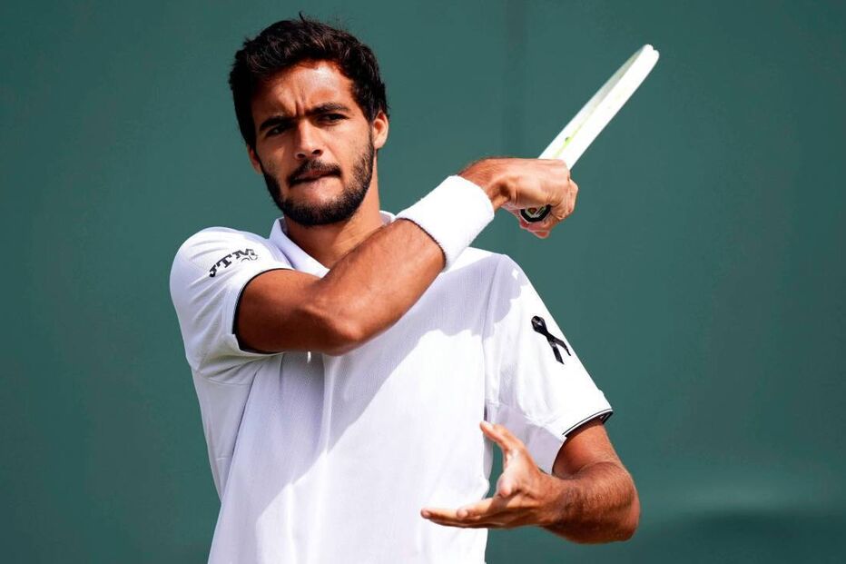 Tenista exibe fita preta em homenagem, empunhando raquete