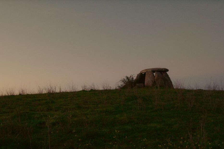 Paisagem campestre com monumento megalítico no topo de um monte
