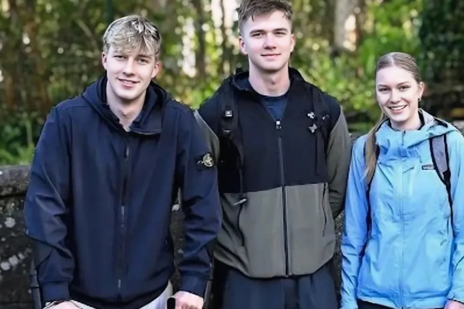 Três jovens posam juntos; um deles usa muletas