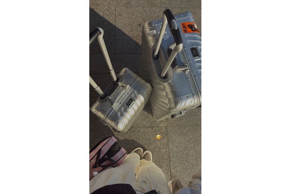 Bagagens prateadas e pés de pessoa num piso cinzento