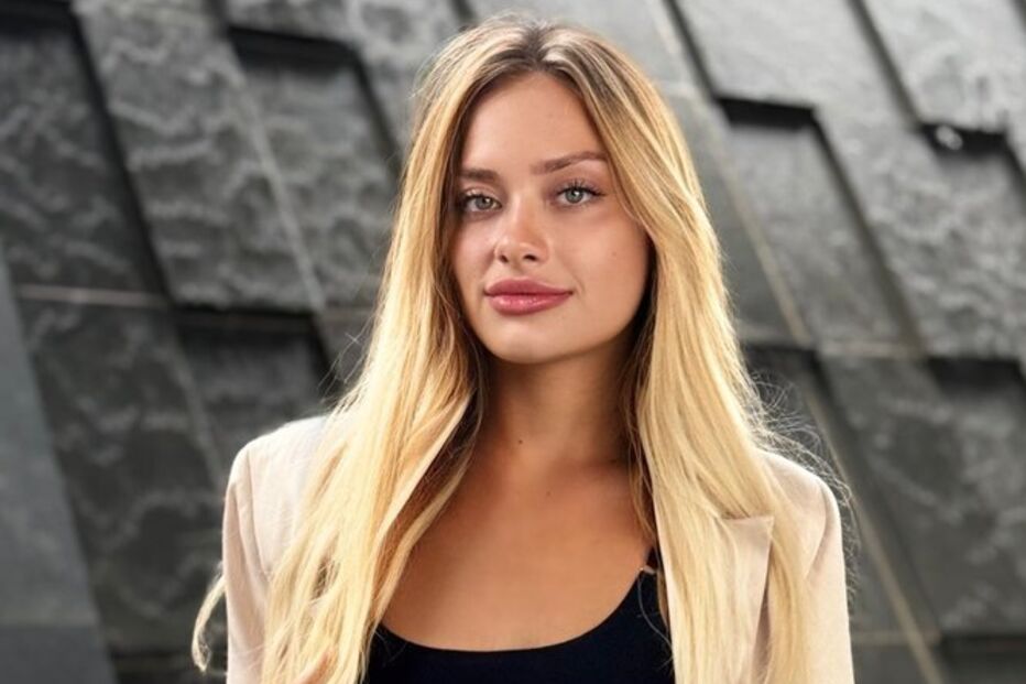 Retrato de uma mulher caucasiana, com um blazer bege e cabelo comprido loiro