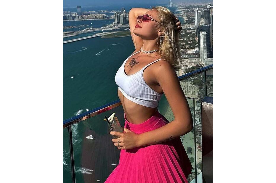 Mulher aproveita vista em Dubai com saia rosa e top branco