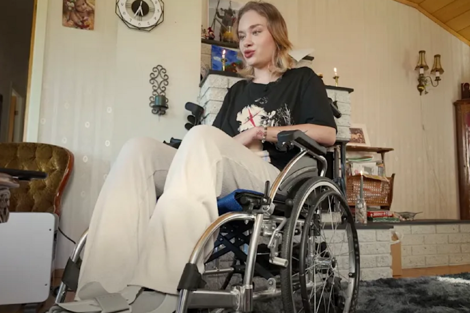 Uma mulher numa cadeira de rodas está dentro de casa